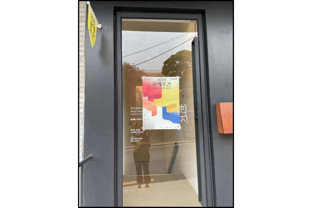 A brightly colored sign on the glass door of Hnaji House 
