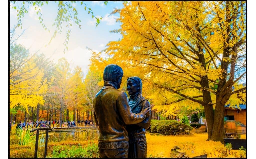 Golden foliage during fall surrounds sculpture of couple
