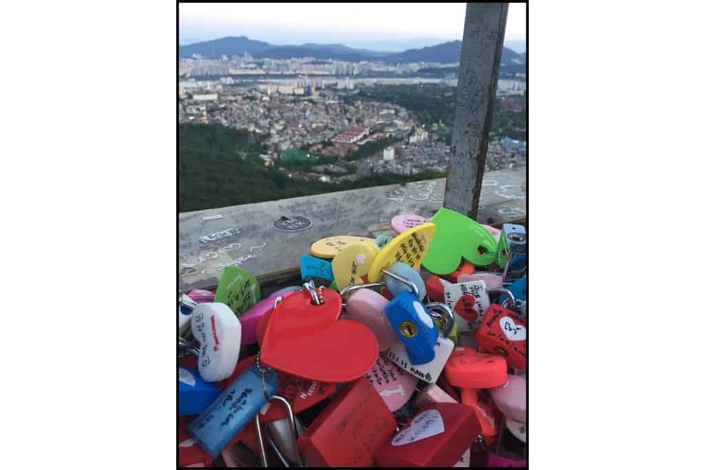 A bunch of "locks of love" locked on the railing in front of a city view 
