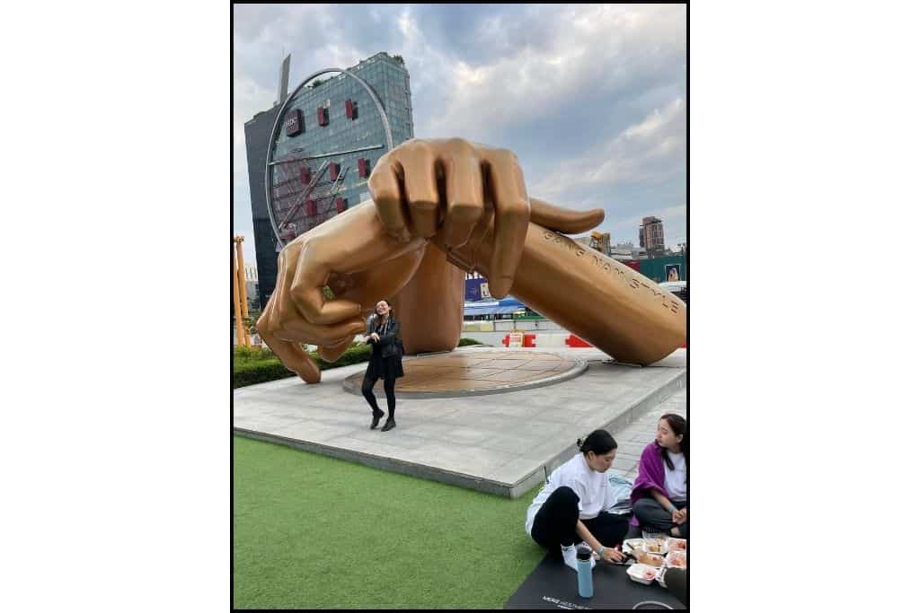 A large bronze colored statue of the Gangnam style hands