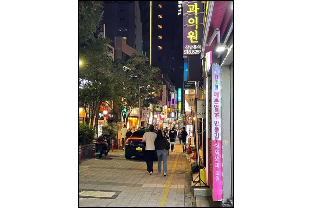 People walking around Seomyone are in Busan at night, under the neon signs of businesses