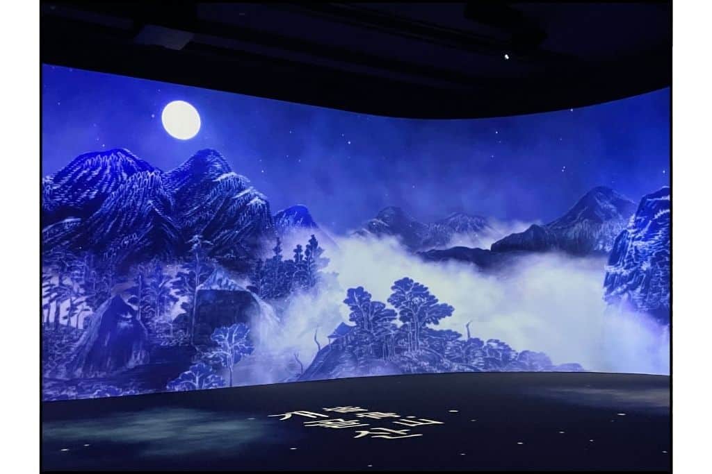 A nighttime scene is blus with a full moon in the immersive digital display at the museum