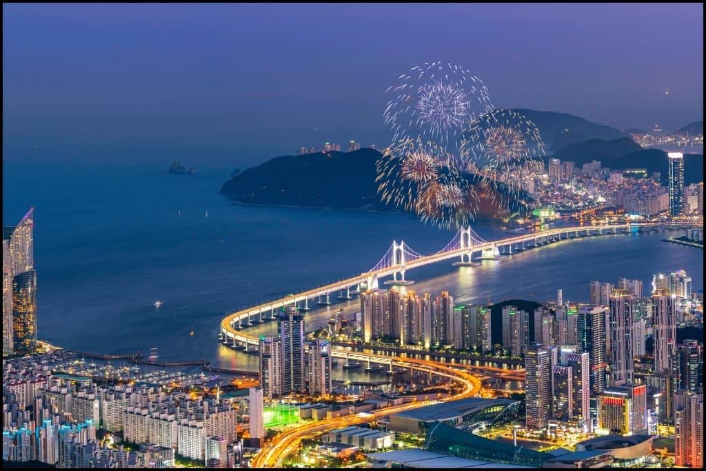 A panoramic nighttime view of beaches in Busan with fireworks.