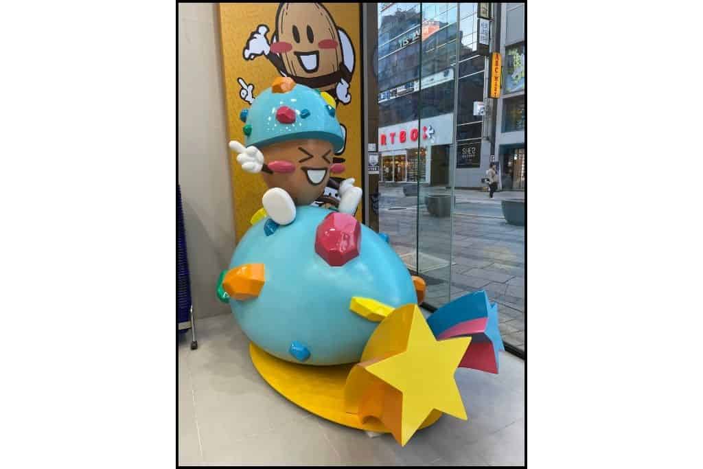 A larger than life-sized model of an almond on a blue chocolate-covered almond of HBAF flavored almonds, a sweet treat found in South Korea