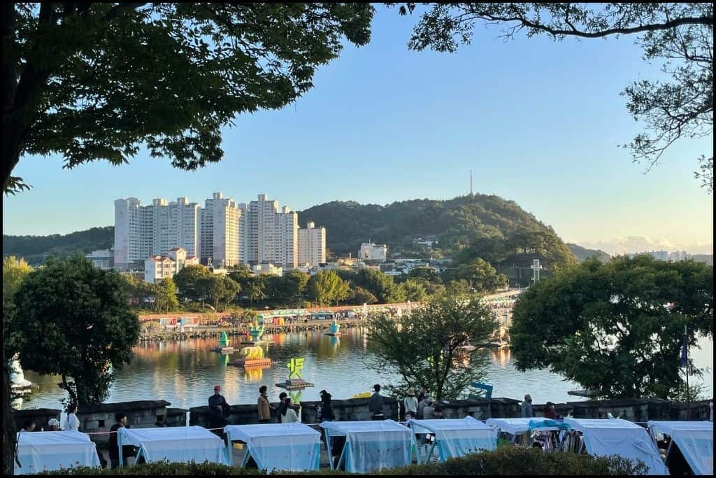 An overview of the river in Jinju, apartment buildings and a lush green hill during the lantern festival, a must-do activity in Jinju