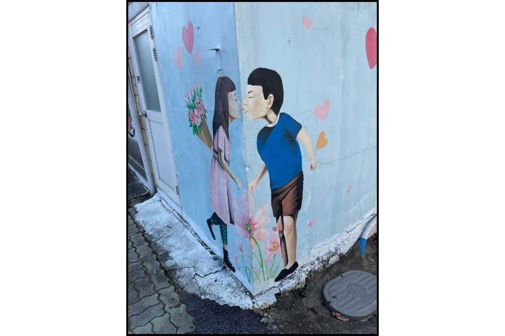An adorable mural on the corner of a building of a boy and girl sharing a kiss in Yeosu