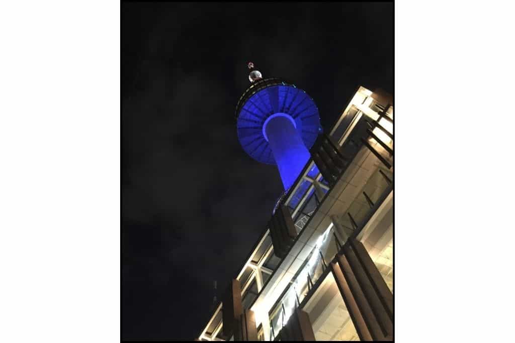 The view from below of Namsan Tower lit up blue at night.