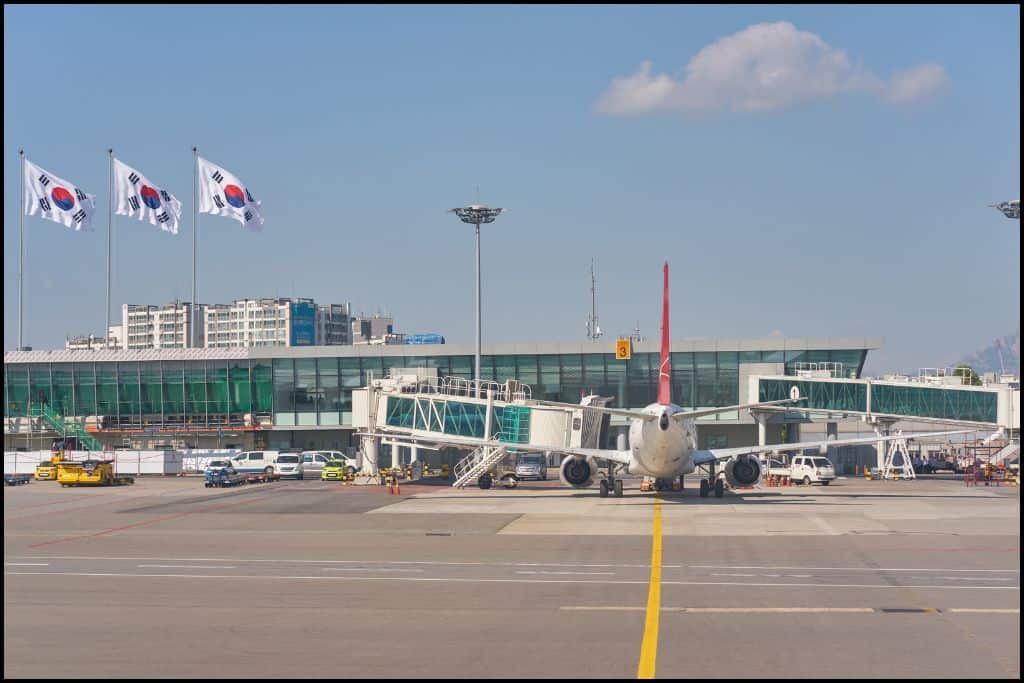A plane parked at the gate of Gimpo Airport in Seoul, South Korea, with a jet bridge connected for passenger boarding, one way to get to Busan from Seoul