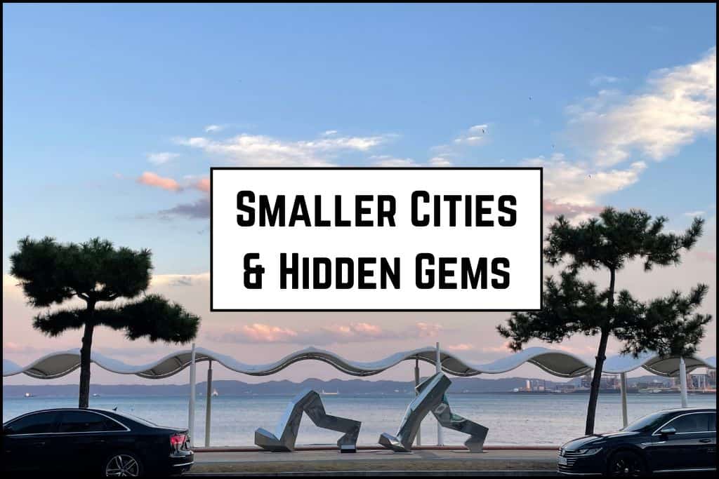 Metal sculpture of walking legs at a Pohang beach during dusk, silhouetted against the fading light with the ocean and sky in the background.