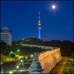 Historic Namsan wall glowing under the city lights with N Seoul Tower in the distance, a popular nighttime activity in Seoul