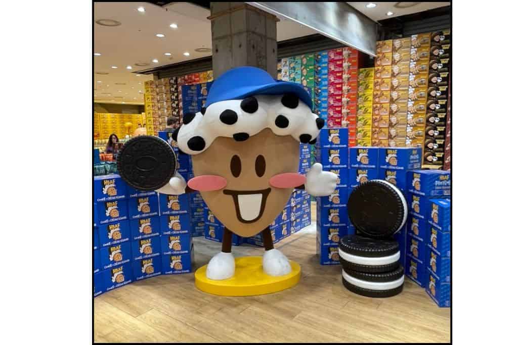 Giant cookie-and-cream almond mascot at an HBAF snack display in Korea, surrounded by colorful boxes and Oreo-themed decorations