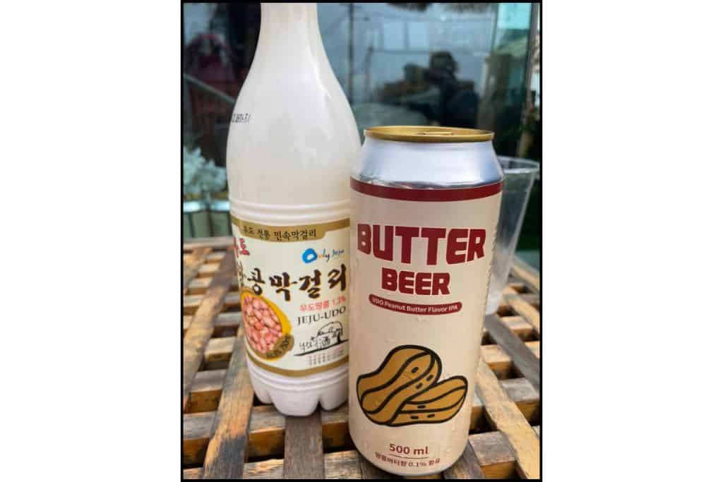 Bottle of Udo Island peanut makgeolli and a can of peanut butter-flavored beer on a wooden table, two popular local drinks from Jeju, South Korea.