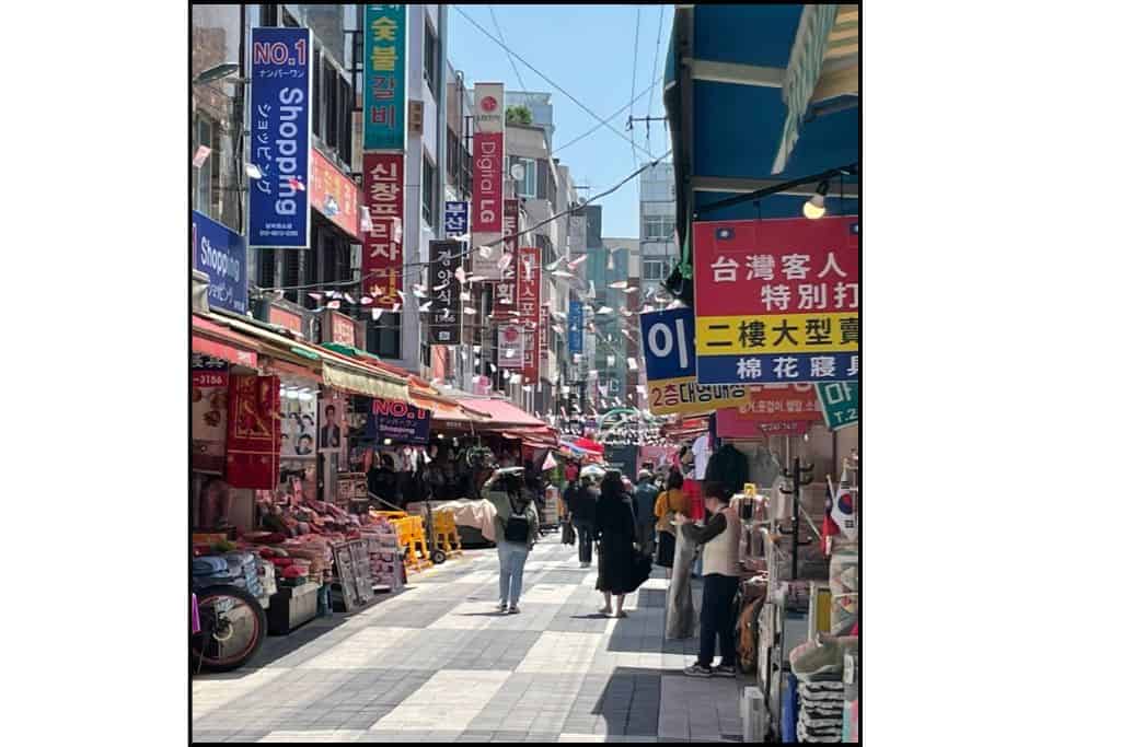 Outdoor market street in South Korea with small shops and colorful signs, a popular spot for cash-only purchases.