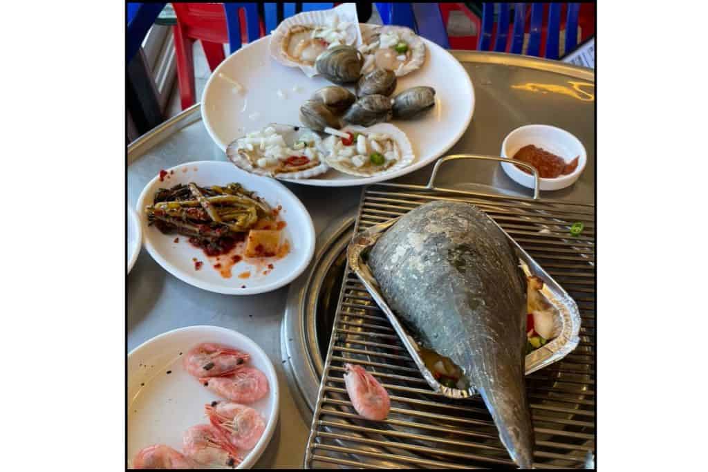 Grilled seafood platter with scallops, clams, shrimp, and ban chan (side dishes) on teh walk to Cheongsapo Daritdol Skywalk at a Haeundae Beach restaurant
