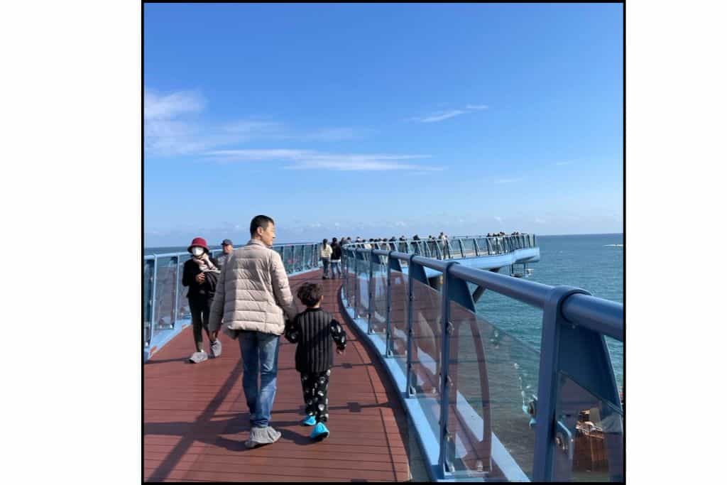 Visitors walking on Cheongsapo Daritdol Skywalk overlooking the ocean near Haeundae Beach.