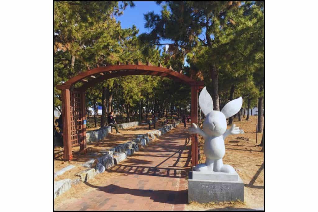Rabbit statue and tree-lined walking path at Haeundae Songrim Park in Busan.