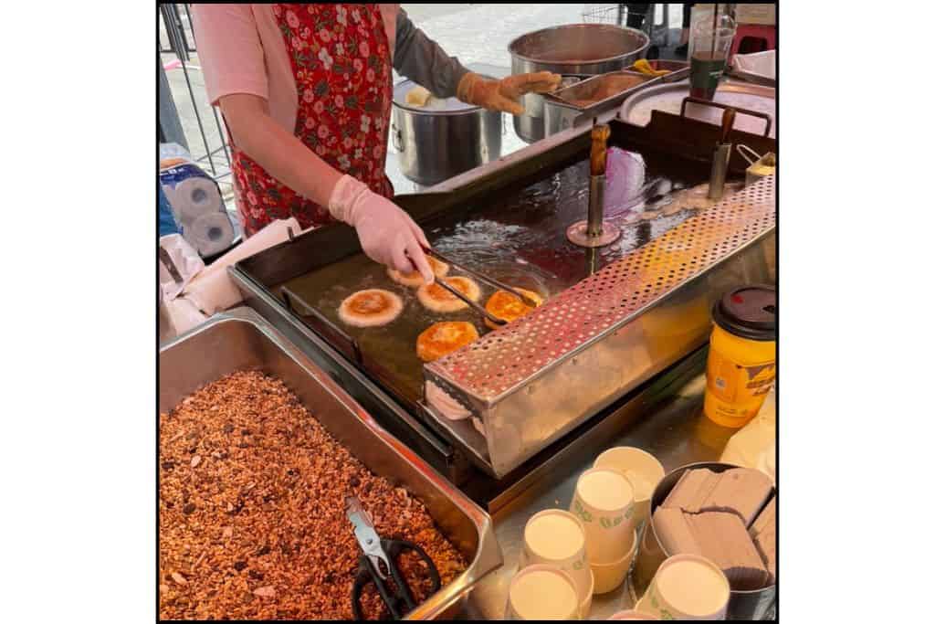 Street vendor frying ssiat hotteok, a Korean stuffed pancake with seeds and nuts, near Haeundae Beach.