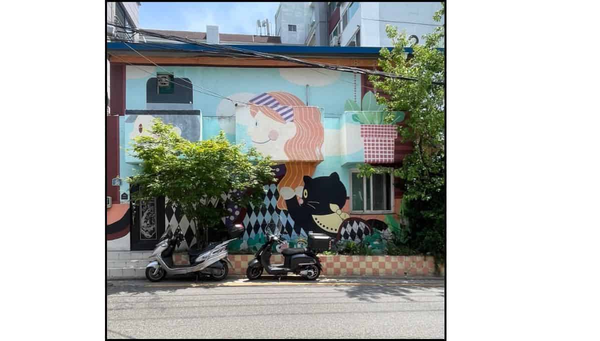 An art mural showing cats on a wall with a scooter parked on the street in front in Itaewon Seoul