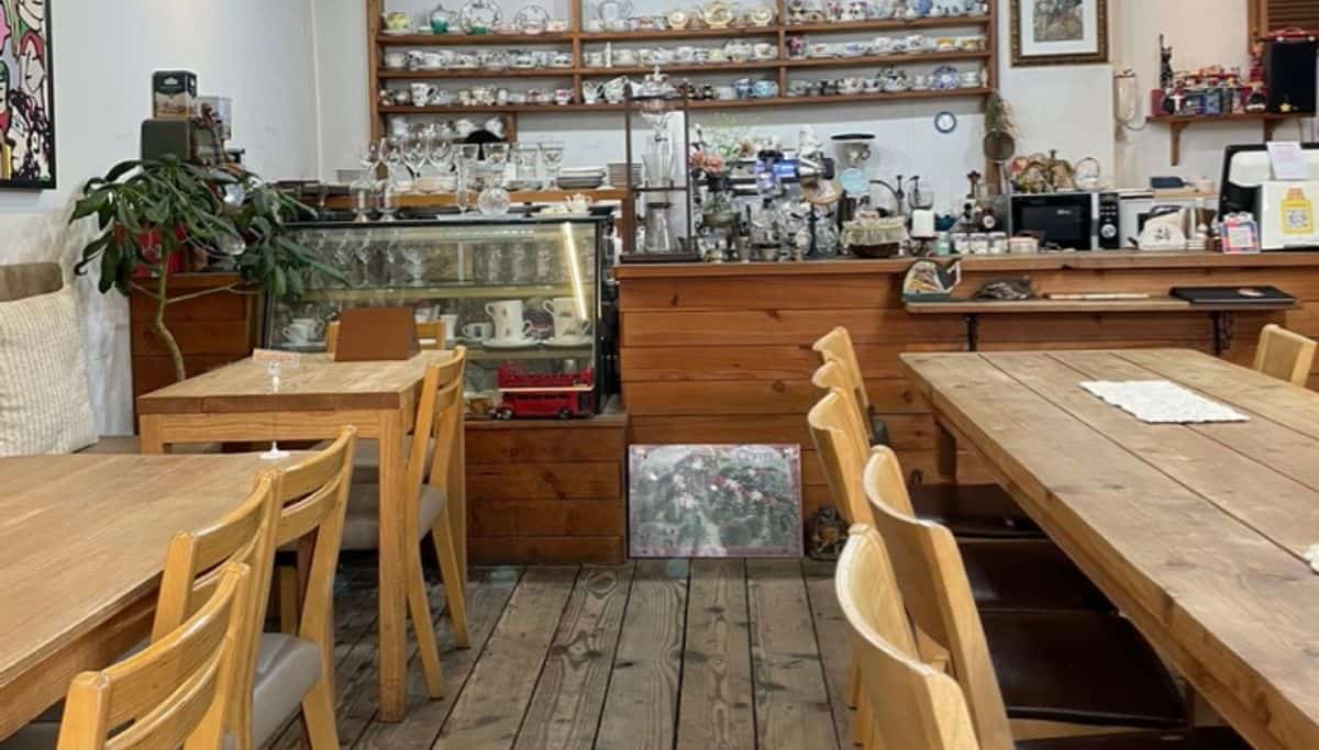 Interior of a traditional Korean café featuring wooden tables, chairs, and shelves with ceramics and vintage decor.
