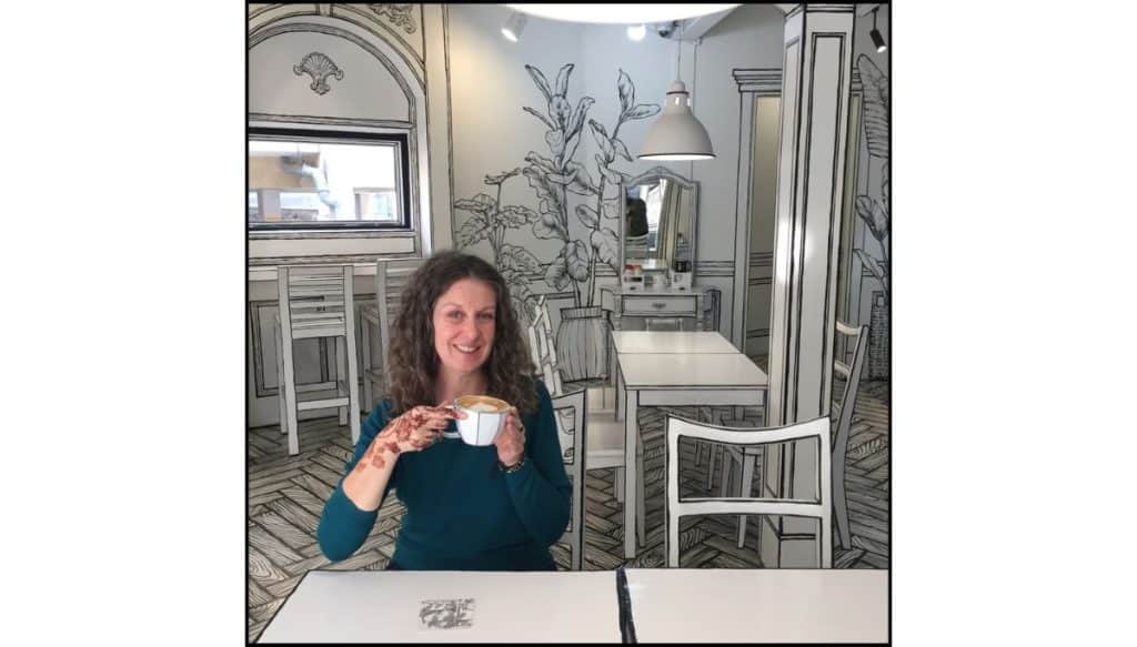 A woman enjoying a latte inside Greem Café in Seoul, a popular 2D cartoon-style café with hand-drawn black-and-white decor.