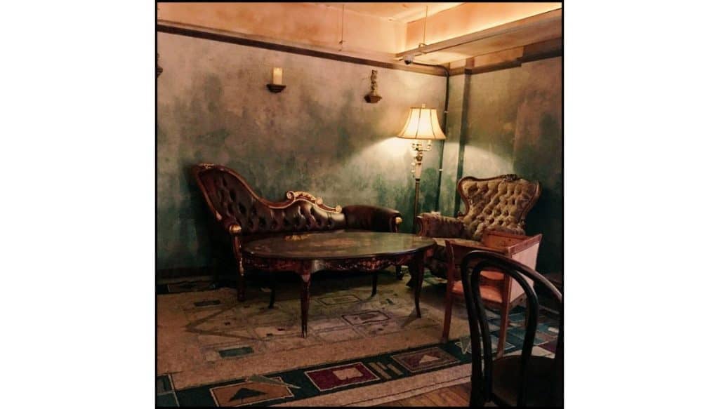 Vintage-style café seating area with antique sofas, dim lighting, and an old-world atmosphere reminiscent of a wizard-themed café.