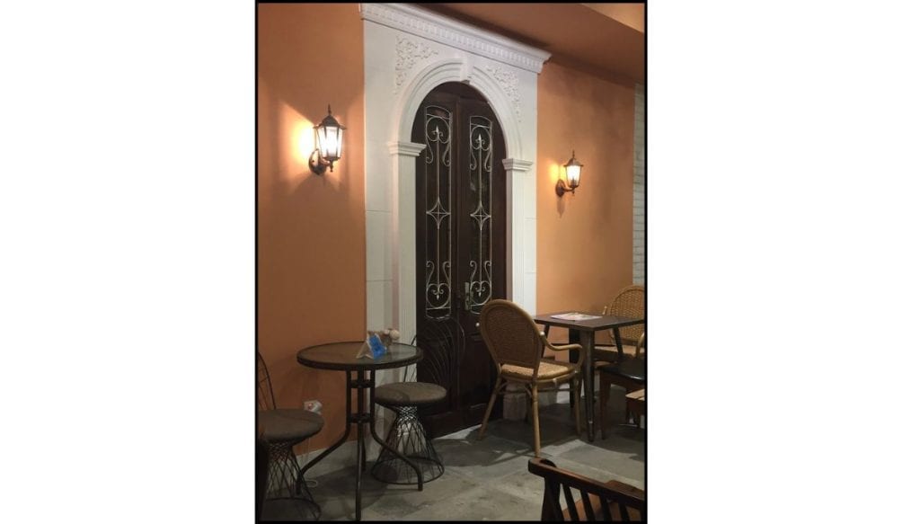 Cozy café seating area with warm lighting, small tables, and decorative arched doors.