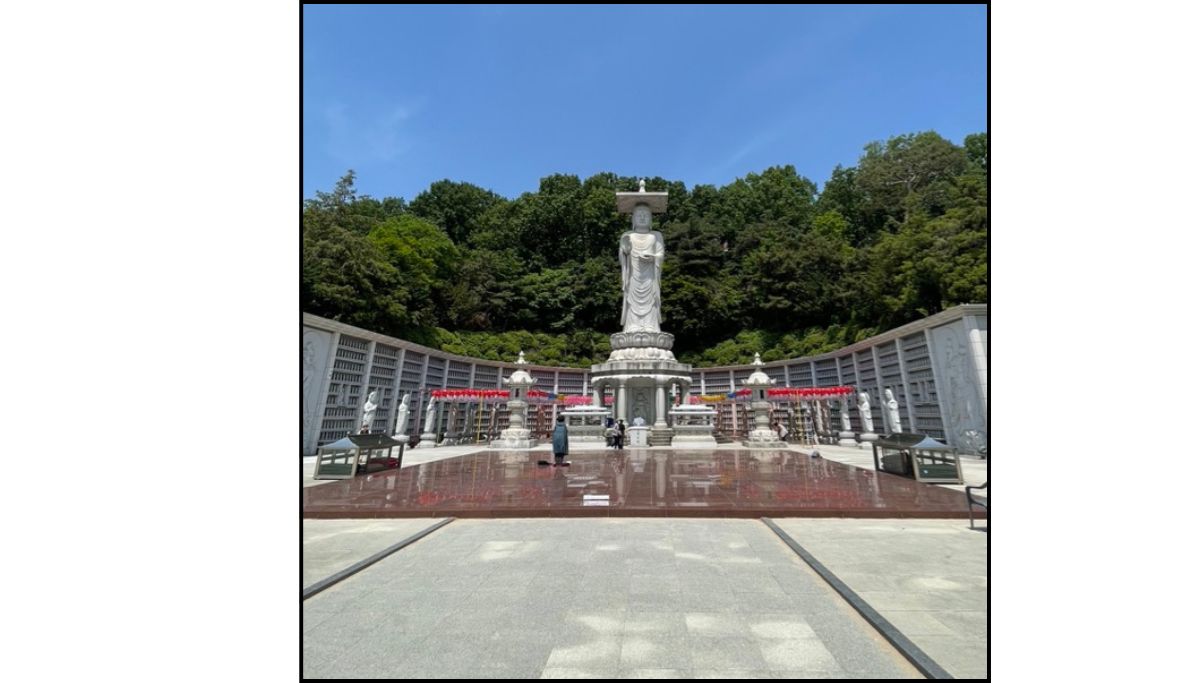 White Buddha statue at Bongeunsa Temple in Gangnam Seoul with forested hillside and temple courtyard