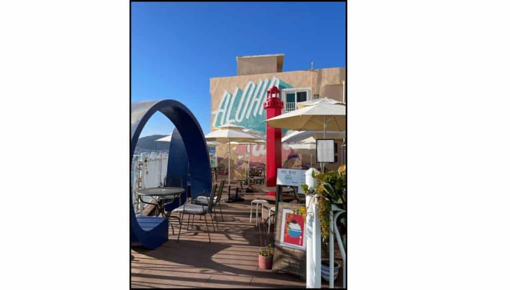 Café patio in Huinnyeoul Culture Village with umbrellas, chairs, and mural on the  wall in the background