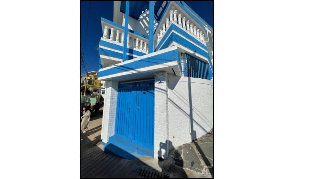 Two-story blue and white house in Huinnyeoul Culture Village, Busan, with decorative railings and a blue entrance