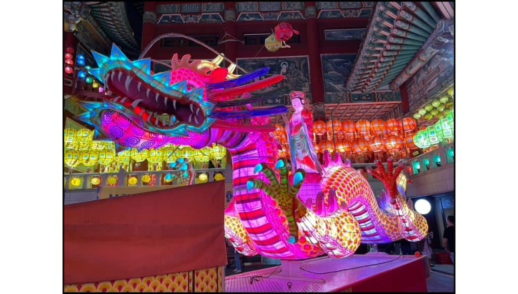 Large illuminated dragon lantern displayed inside Samgwangsa Temple, surrounded by colorful lotus lanterns during the Buddha’s Birthday festival.
