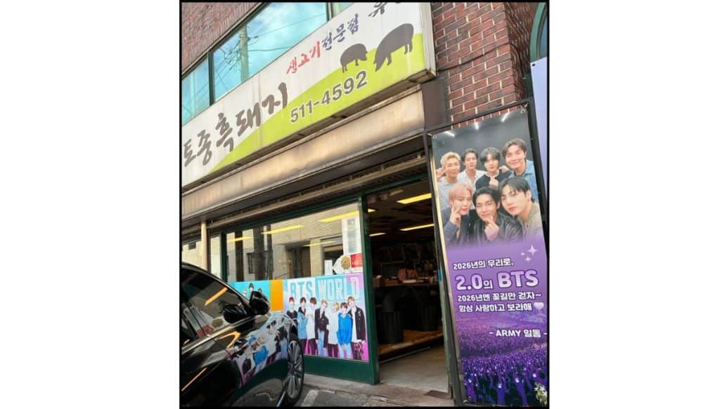 Exterior of Yoojung Sikdang in Seoul with BTS posters displayed beside the restaurant entrance