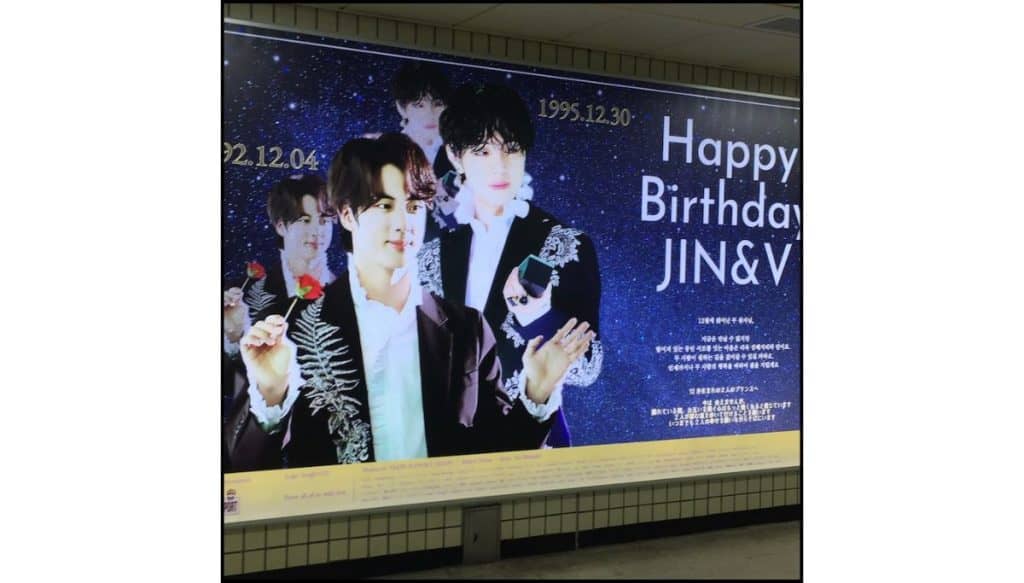 Subway station birthday billboard celebrating Jin and V of BTS with large portrait photos and Happy Birthday message in Seoul.