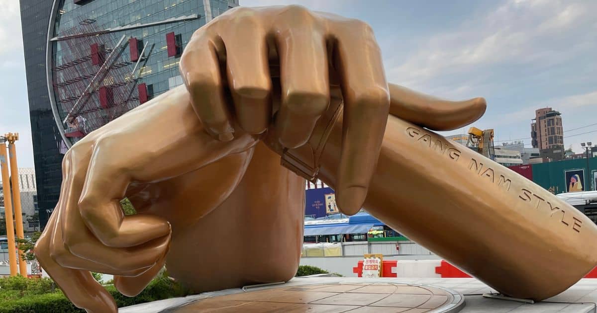 Large bronze sculpture of crossed hands making the Gangnam Style pose outside a building in Seoul.