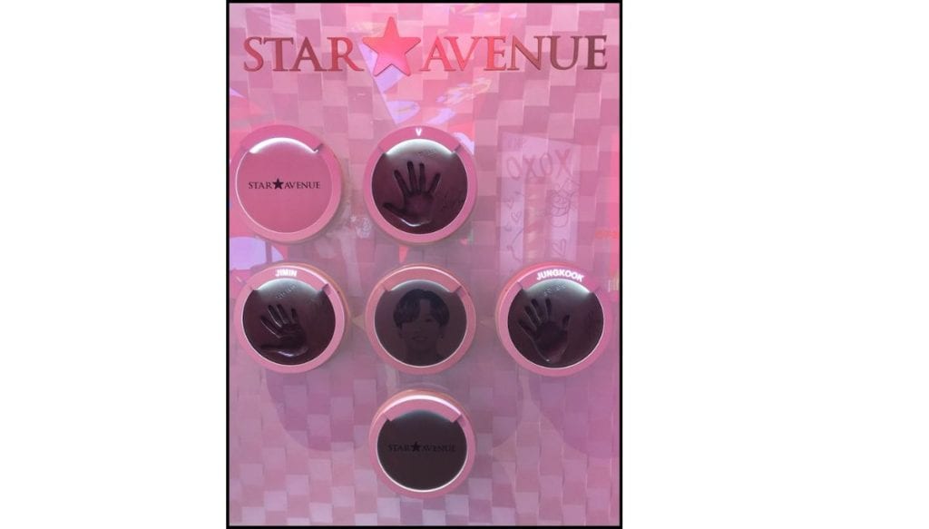 Pink wall display at Lotte Star Avenue in Myeongdong featuring BTS handprint plaques labeled V, Jimin, and Jungkook.