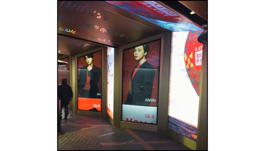 Star Avenue digital billboards displaying large BTS images of Jin and Jimin in a covered walkway.