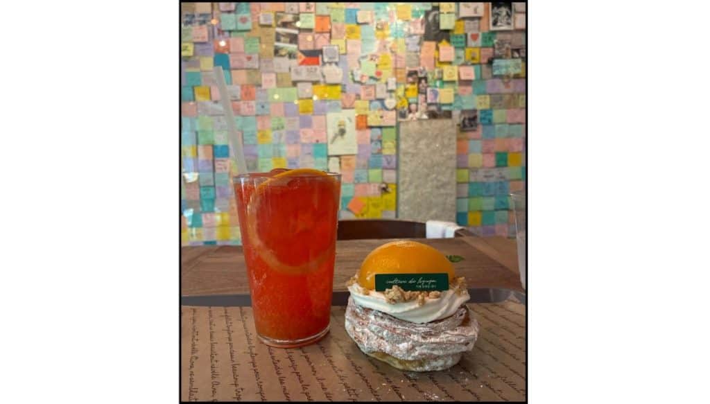 Grapefruit soda and peach pastry on a table at Hyuga Cafe in Gangnam, Seoul, with a wall covered in colorful BTS fan notes in the background