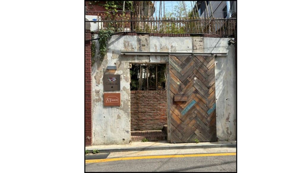 Weathered brick and concrete entrance to Hyuga Cafe in Gangnam, Seoul, with stairs leading up to the former BTS dorm building
