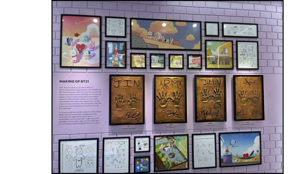 A purple wall containing the drawings of BT12 characters and BTS handprints in bronze at LINE Friends store