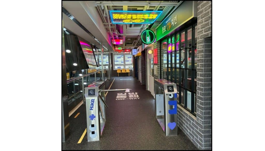 Indoor Seoul street-style set with subway turnstiles, neon signs, storefronts, and a one-way road marking inside HiKR Ground.