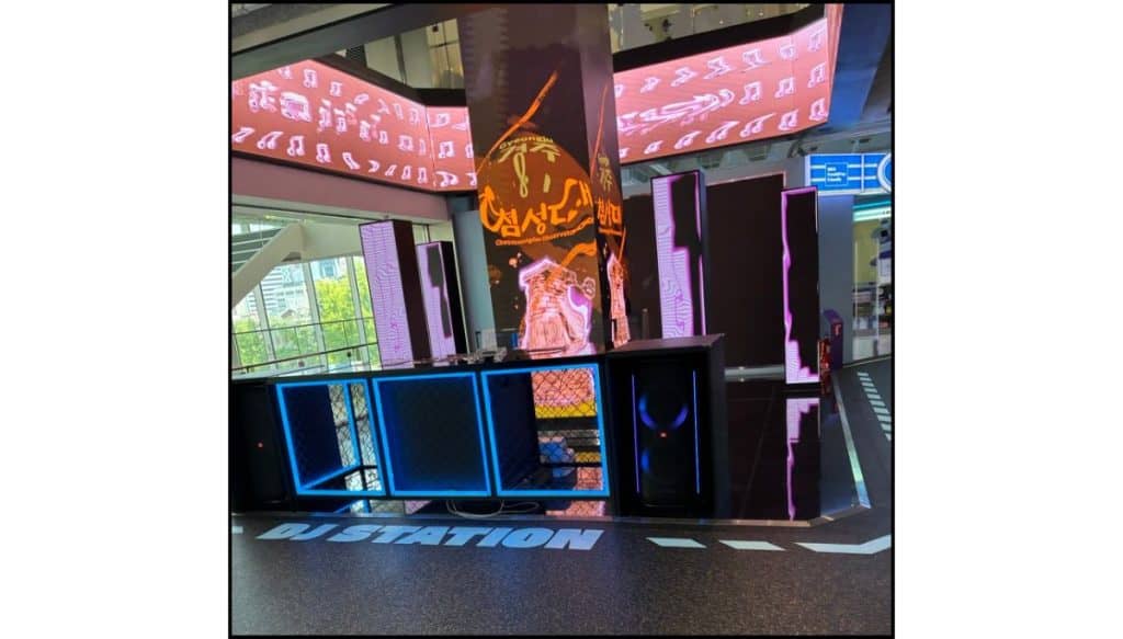DJ booth set with glowing screens, purple lighting, and colorful HiKR graphics on the walls.