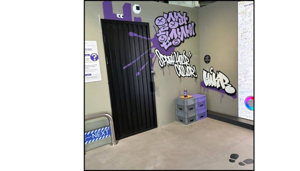 Small graffiti-style photo area with a black door, purple lighting, and spray-paint lettering on the wall.