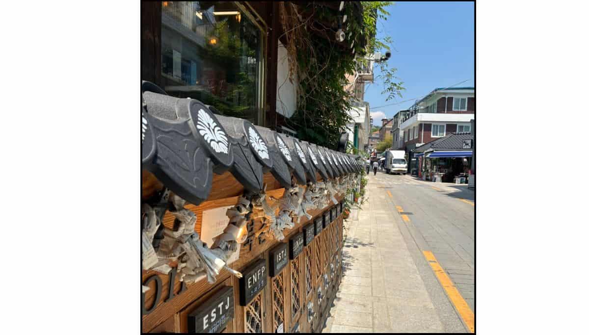 A traditional Korean tiled roofline decorated with personality type signs along a sunny street in Insadong, Seoul.