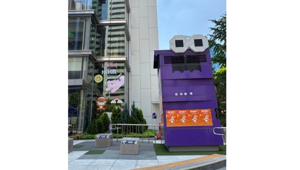 Outside HiKR Ground in Seoul, a large purple character display stands near the entrance beside HiKR signs and colorful K-culture window decorations.