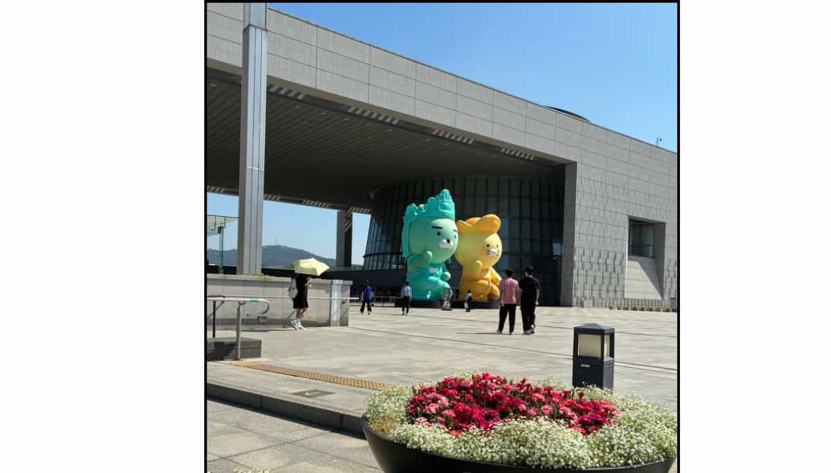 Two large character displays standing outside the National Museum of Korea, with a flower planter in the foreground in Seoul