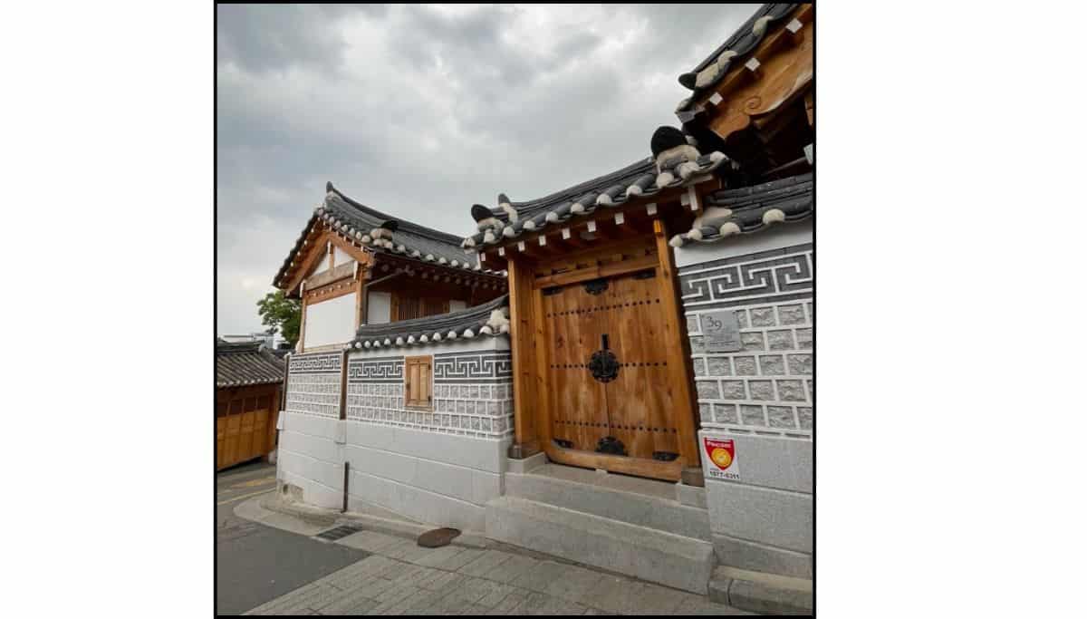 Traditional Korean hanok house with wooden gate and tiled roof in Bukchon Hanok Village, Seoul.