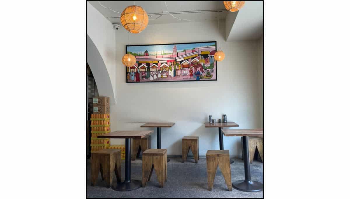 Inside a cozy restaurant in Itaewon with wooden stools, small tables, hanging lanterns, and colorful wall art.