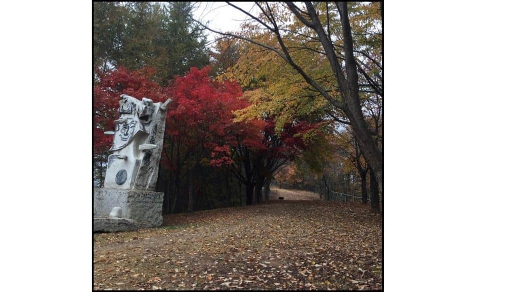 Autumn foliage and sculpture along a wooded path at Gonjiam Ceramic Park in Gonjiam, South Korea.