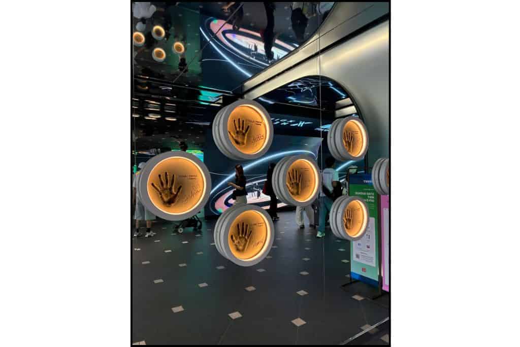 Illuminated bronze handprints and signatures of K-pop stars displayed on a mirrored wall at Lotte World Star Avenue in Seoul.